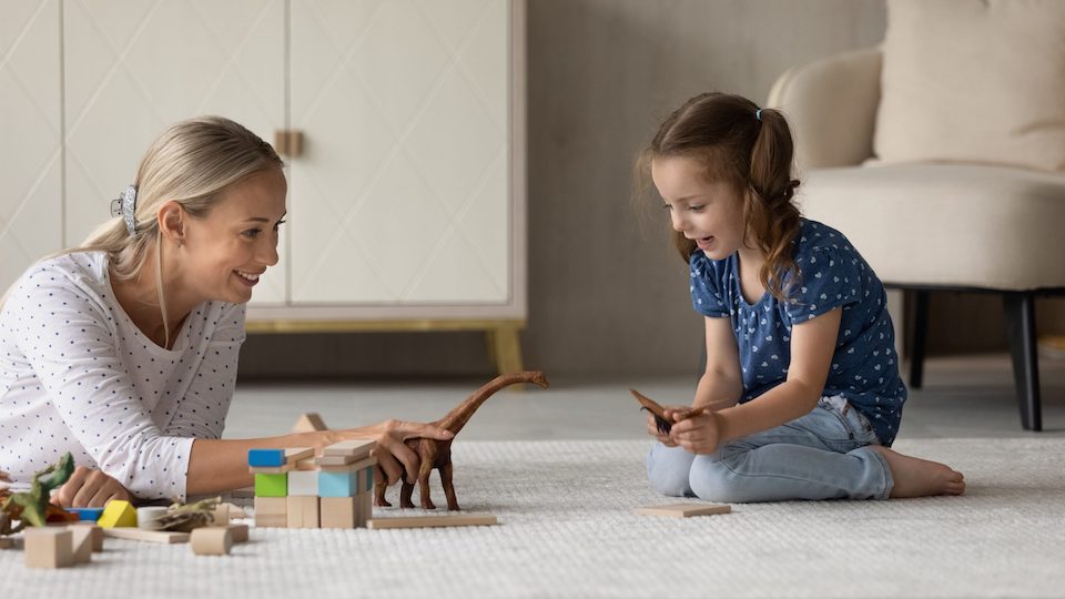 Woman and child play with games on the floor of a home