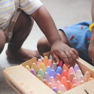 two children play with coloured chalk